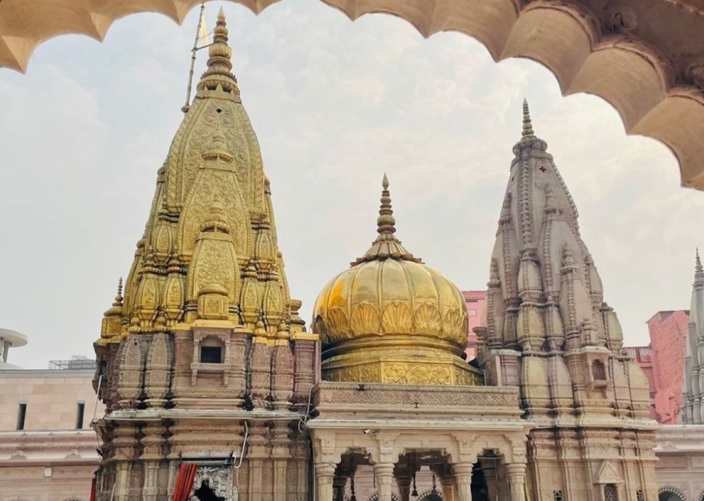 A stunning close-up view of the Shri Kashi Vishwanath Jyotirlinga Temple in Varanasi, showcasing its towering golden shikhara gleaming under soft sunlight.